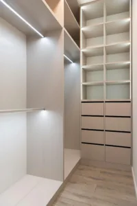 Interior of modern light wardrobe with big cabinets with shelves with lamps in apartment