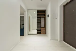 Contemporary corridor interior with empty shelves in closet with mirror reflecting floor and lamps at home