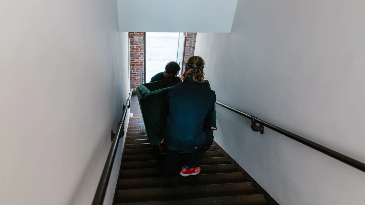 Ein Sofa wird vorsichtig durch ein enges Treppenhaus getragen