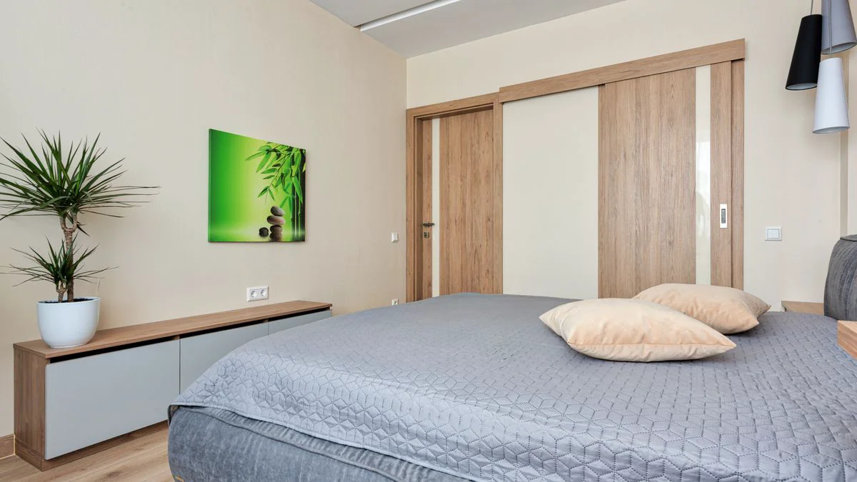 Offener Kleiderschrank mit Schiebetüren, Schubladen und Kleiderstangen in einem hellen Raum