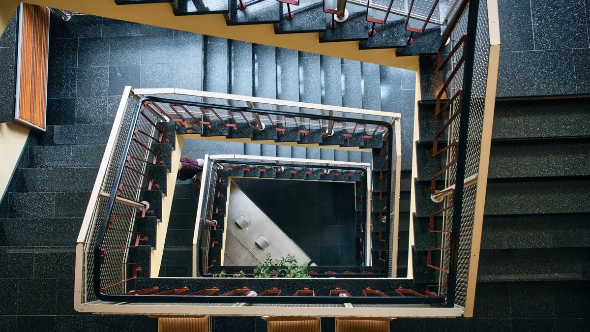Zwei Möbelträger tragen ein großes Sofa durch ein enges Treppenhaus in Berlin