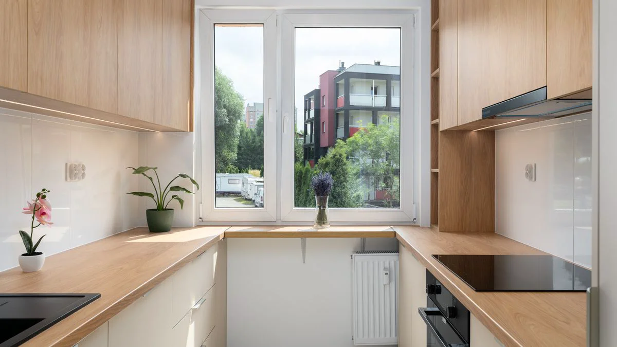 Kleine Küche mit Fenster über der Arbeitsfläche und schmalem Durchgang.